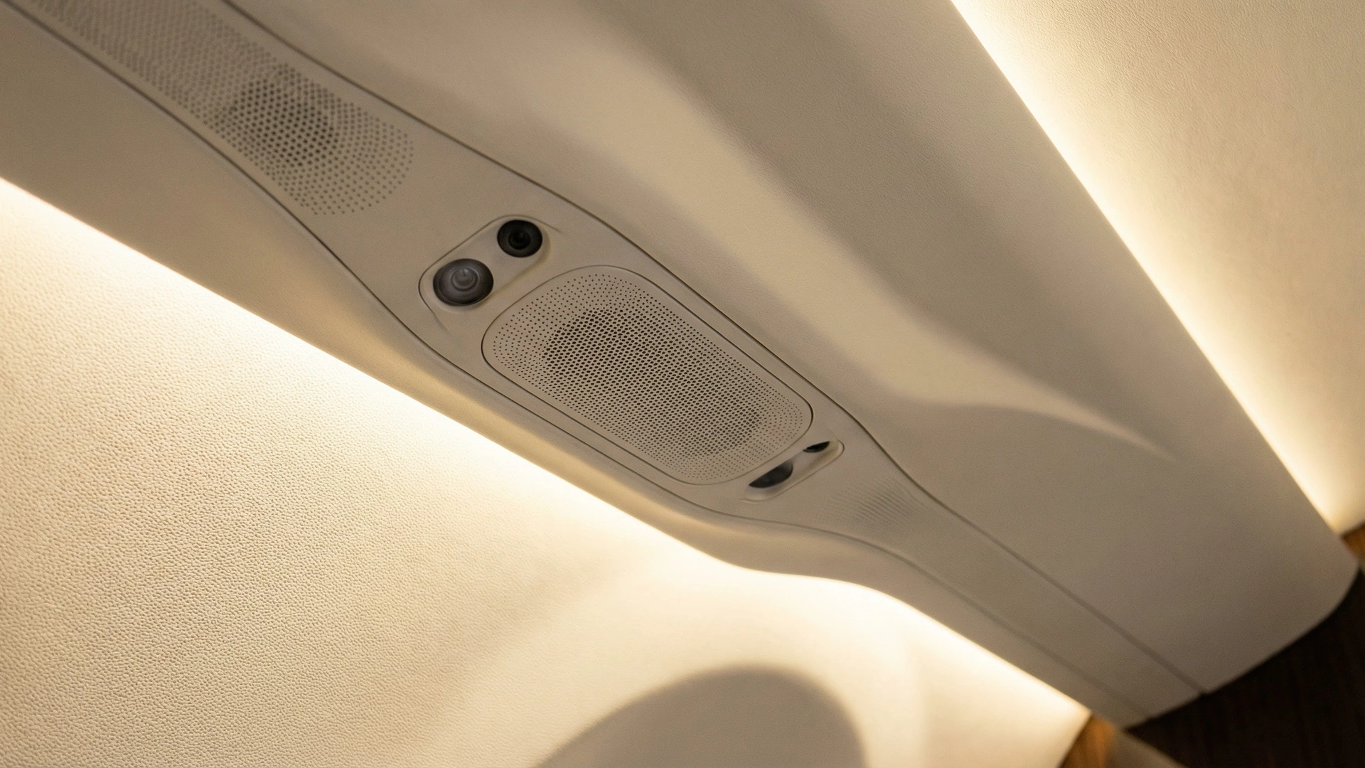 Private jet cabin ceiling with integrated active noise cancellation speaker array flush-mounted in premium composite panel