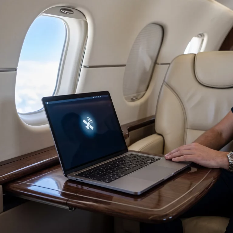 Private jet cabin interior showing laptop and satellite connectivity during flight