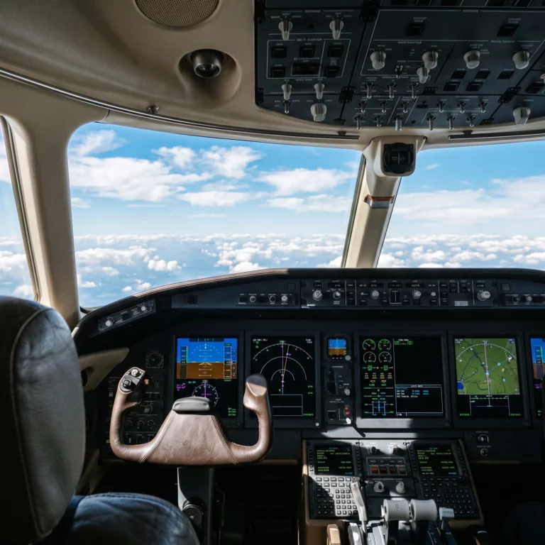 Cockpit view of a private jet with glowing avionics displays during daylight flight