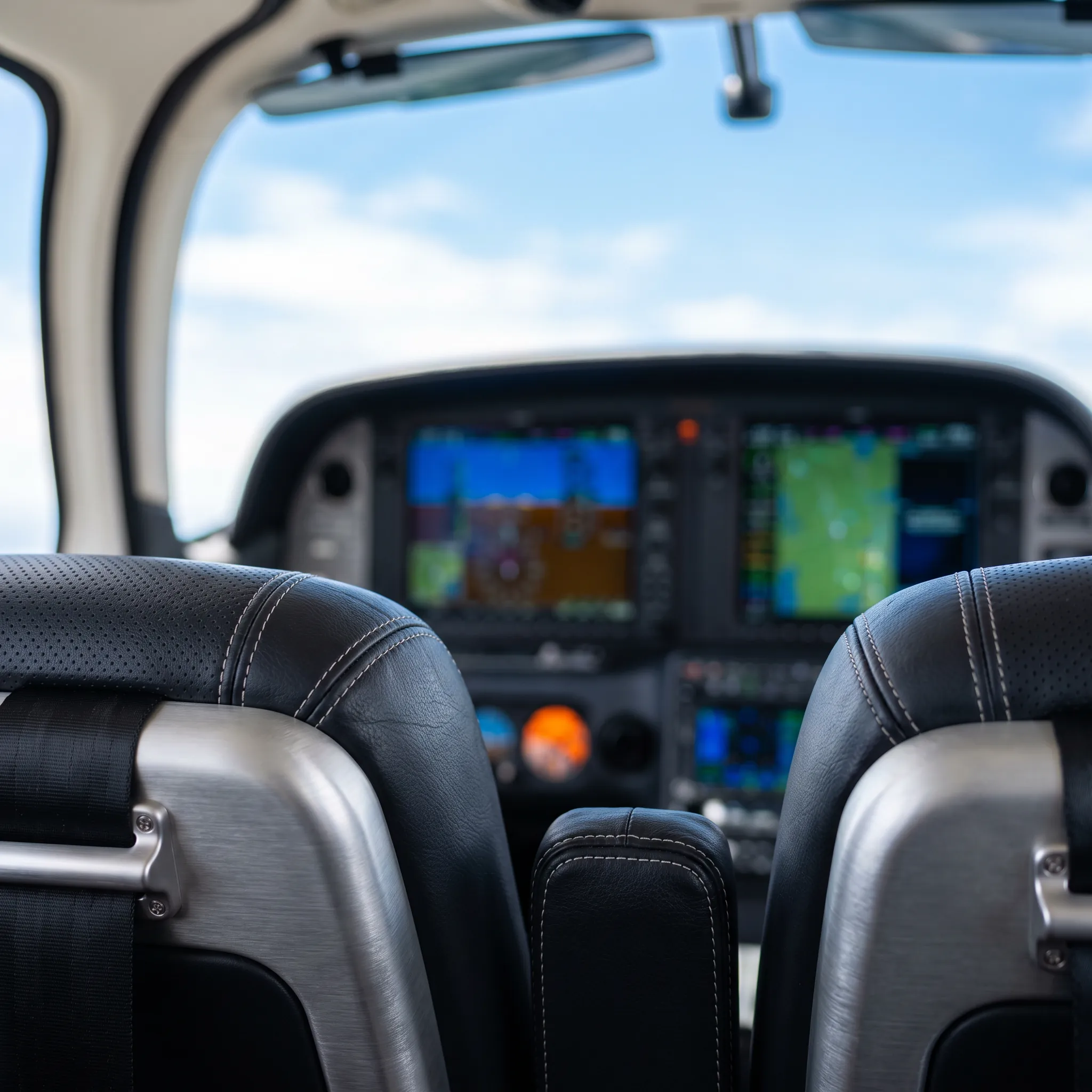 Unoccupied cockpit interior of a Cirrus aircraft with glass avionics displays glowing softly