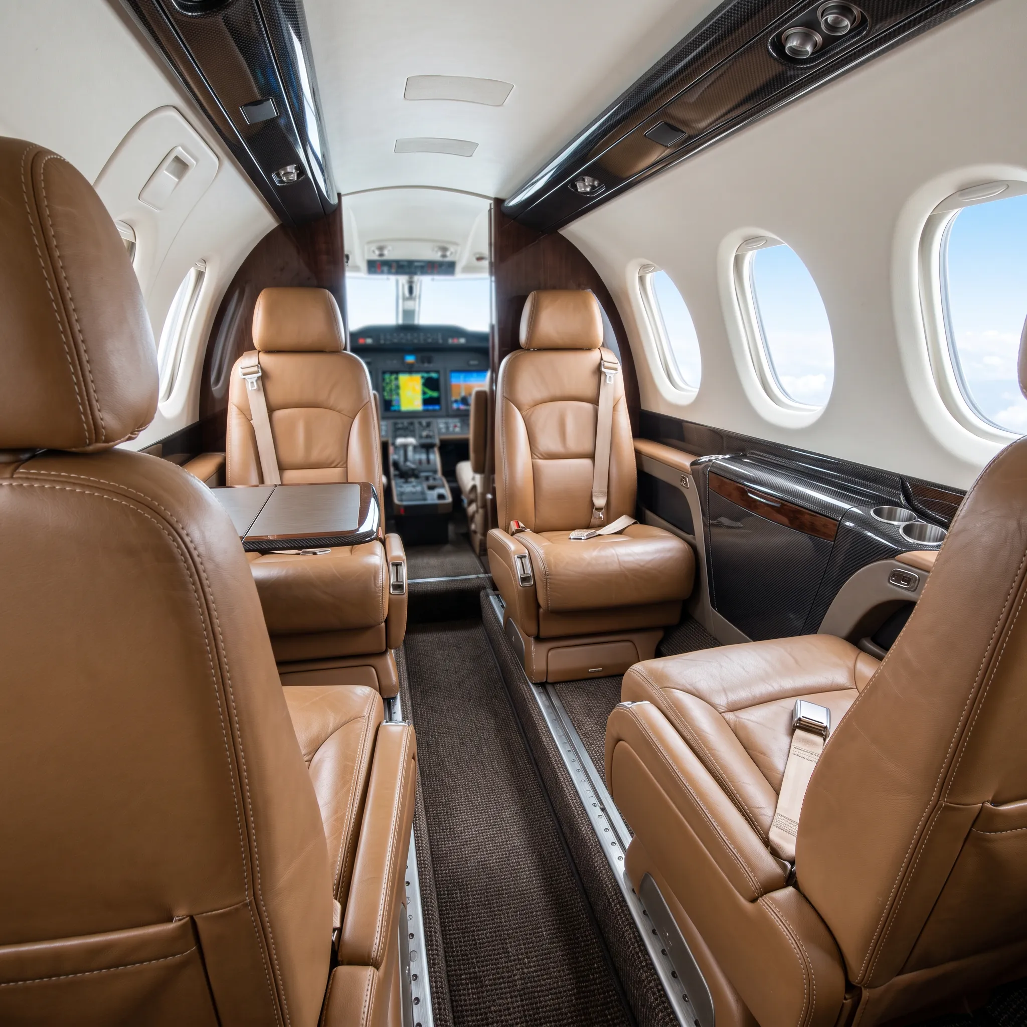 Light jet cabin interior with leather club seats and natural daylight through oval windows