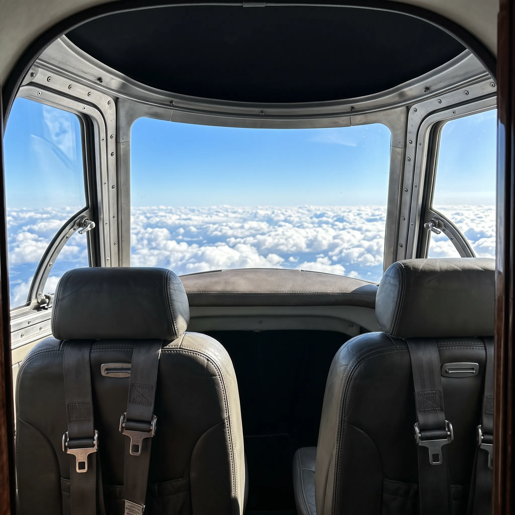 Unoccupied light jet flight deck viewed from the cabin with clear sky through the windscreen